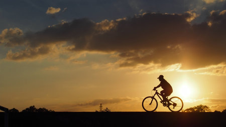 A woman rides a bicycle on the road when sunset: silhouette photoの写真素材