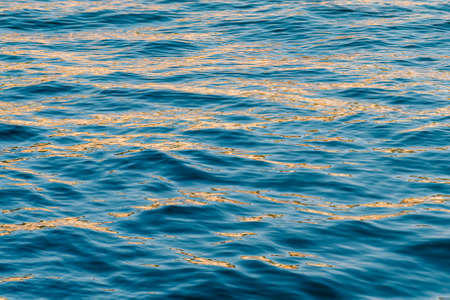 Golden sunlight reflected on deep blue sea. Minimal summer holiday composition.の写真素材