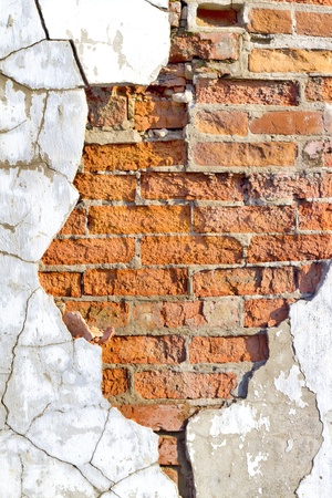 old brick wall with crumbling plaster crackedの写真素材