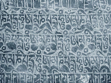 Buddhist mantra carved in stone as backgroundの写真素材