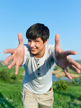 cheerful guy with outstretched arms outdoorsの写真素材