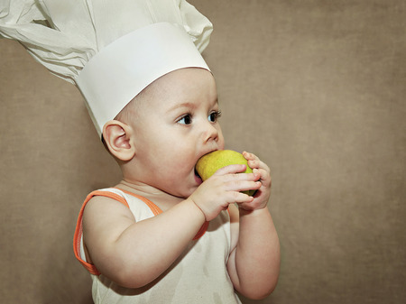 little baby in a chef's hat eating a pearの写真素材
