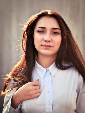 Portrait of a young pretty girl in a light shirt and with her hair outdoorsの写真素材