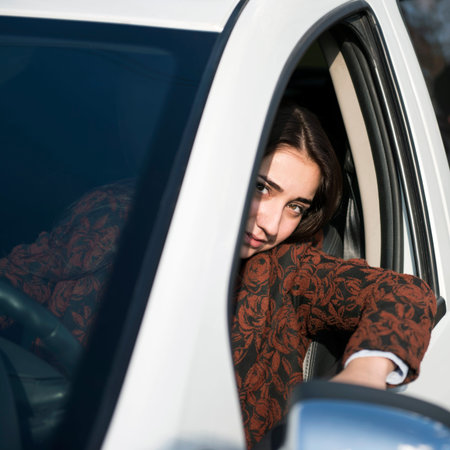 Young pretty smiling girl sitting behind the wheel of a car