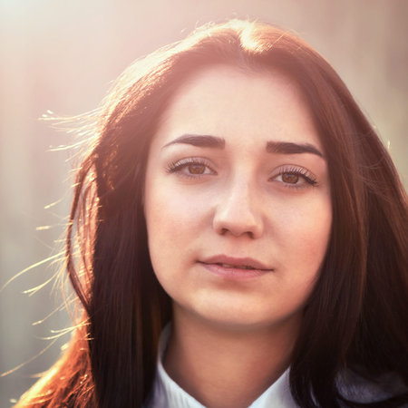 Portrait of a young pretty girl in a light shirt and with her hair outdoorsの写真素材