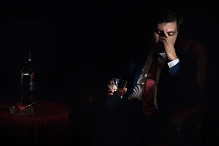 businessman in an armchair indulges in despondency and drinks alcoholの写真素材