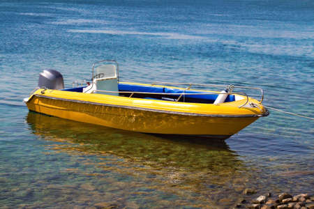 yellow motor boat moored to the sea shoreの写真素材