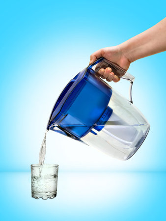 Water is poured into a transparent glass beaker from a jug-filterの写真素材