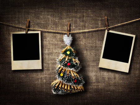 Old style photographs and Christmas tree hanging on a clothesline on a linen backgroundの写真素材