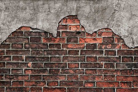 Half-fallen cement plaster on an old brick wall as a vintage grunge backgroundの写真素材