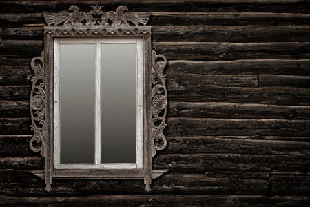 antique wooden carved window frame on an old log wallの写真素材