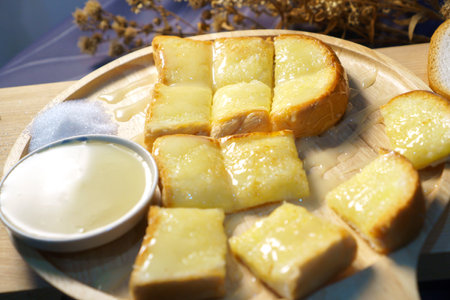 Toast bread with butter and honey on wooden plateの写真素材