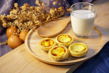 Egg tart with a glass of milk on a wooden tableの写真素材