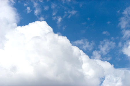 Captivating stock photo featuring a serene blue sky adorned with fluffy white clouds, creating a...