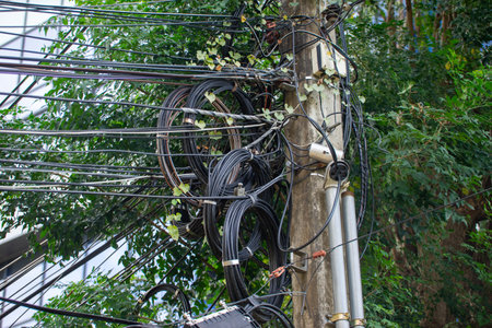 An electrical pole that shows the disorder in the arrangement of the cables.
