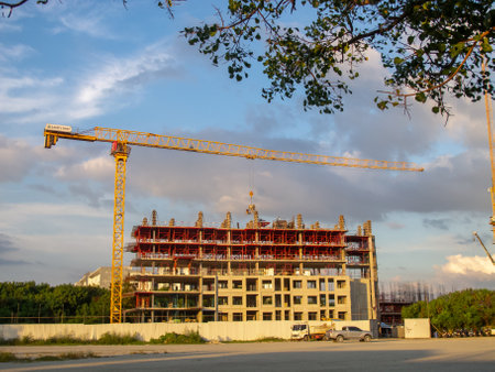 A construction site featuring a large crane and a building under development during sunset. This image captures the essence of urban growth and industrial progress.の写真素材