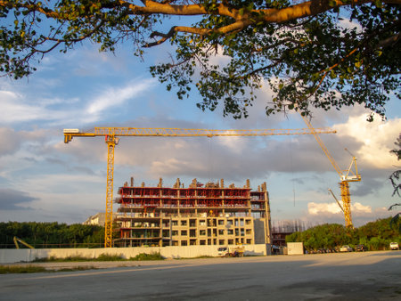 A vibrant construction site featuring two cranes and an unfinished building surrounded by a clear sky, showcasing urban development and progress in the industry.の写真素材