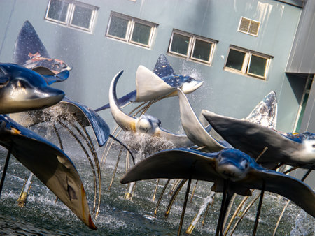 This captivating image showcases a dynamic sculpture of metallic rays gracefully swimming through an urban fountain, creating a serene and intriguing atmosphere.の写真素材