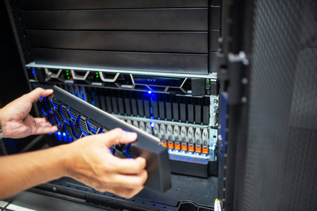 A technician is seen handling a data storage device inside a modern server room, showcasing essential IT equipment and advanced technology in action.の写真素材