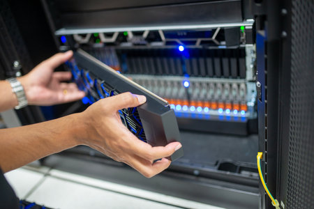 A technician is carefully installing a data storage device in a server room rack. The modern infrastructure supports efficient data management and storage solutions.の写真素材
