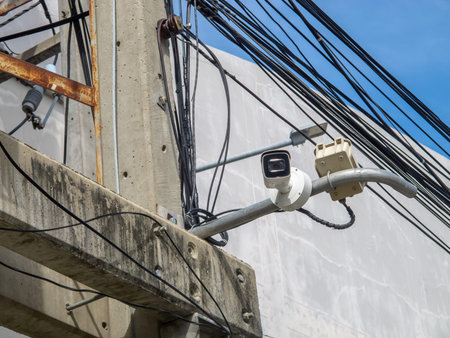 A detailed view of a surveillance camera mounted on a concrete utility pole amidst a network of...