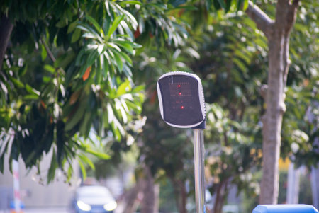 A modern traffic signal stands prominently in an urban setting, surrounded by lush greenery. This image captures the blend of technology and nature in city life.の写真素材