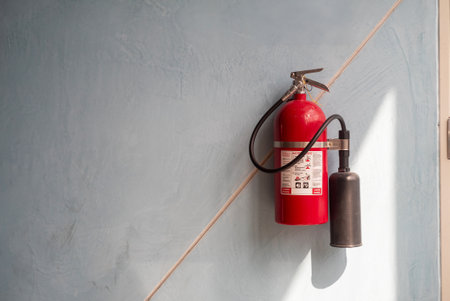 A bright red fire extinguisher is mounted on a textured blue wall, highlighting its importance in fire safety and emergency preparedness.の写真素材