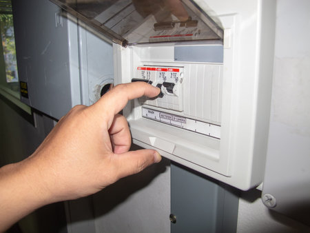 A hand is adjusting an electrical circuit breaker in a residential control panel. The image...
