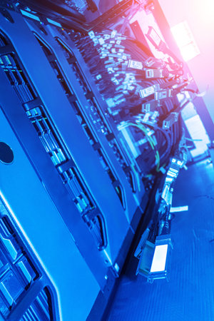 This image showcases advanced server equipment in a data center, illuminated by blue light. Cables...