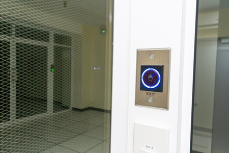 A close-up view of a modern exit button set against a sleek glass wall in a contemporary office...