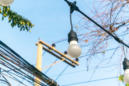 A close-up view of decorative hanging lights against a blue sky, showcasing details of bulbs and...