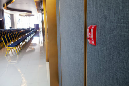 An interior view showcasing a modern design featuring an emergency alarm on the wall and rows of empty seating, creating a sleek and inviting atmosphere for events.の写真素材