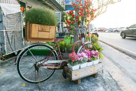 Vintage bicycle adorned with vibrant flowers in wooden boxes creates a charming urban scene. This unique display offers a blend of nature and creativity in an outdoor setting.の写真素材