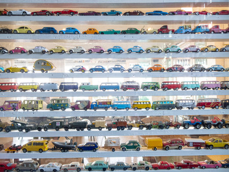 A vibrant display of vintage toy cars arranged neatly on a wooden shelf, showcasing their colorful...