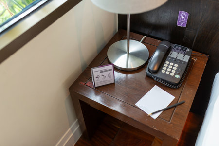 A stylish hotel room nightstand featuring a modern lamp and telephone, perfect for guests. The inviting space is ideal for relaxation and convenience.の写真素材