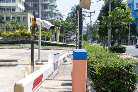 This image showcases a parking barrier arm accompanied by a security camera in a bustling urban area. The scene highlights modern infrastructure and surveillance technology.の写真素材