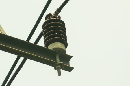 Close-up view of a power line insulator against a clear sky. This image showcases electrical infrastructure, highlighting the insulator's design and function.の写真素材