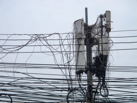 This image captures an overgrown communication tower with tangled wires, showcasing the complexities of urban infrastructure and the juxtaposition of technology and nature.の写真素材