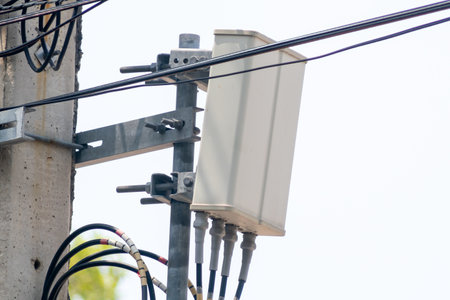 A close-up view of telecommunication equipment mounted on a utility pole, showcasing the intricate wiring and connections essential for network transmission.の写真素材