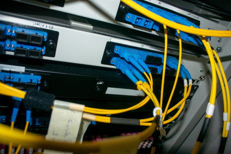 Close-up view of fiber optic cables connecting network equipment in a server rack, highlighting...