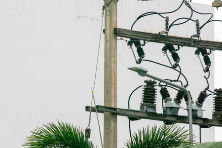 Close-up view of power lines and electrical equipment on a utility pole, set against a simple...