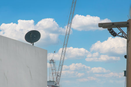 A serene urban landscape featuring a construction crane against a backdrop of fluffy clouds and a blue sky, highlighting modernity and infrastructure elements.の写真素材