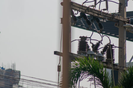 Urban power lines and electrical equipment shown against a cloudy backdrop. The image captures the...