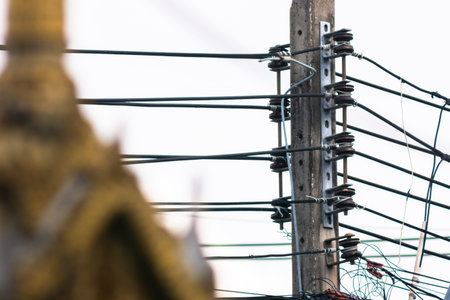 A close-up view of an electrical pole showcasing intricate power lines and cable connections. The...