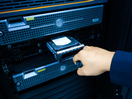 A technician inserts a hard drive into a server cabinet, illustrating technology and data management processes in a modern computing environment.の写真素材