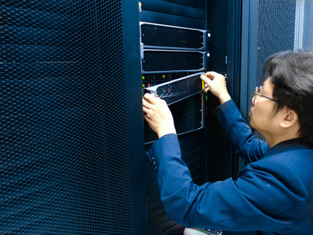 Young asian man working in data center server room with network equipmentの写真素材