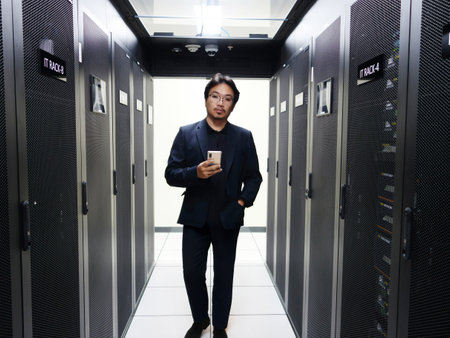 young handsome asian business man in datacenter server room with mobile phoneの写真素材