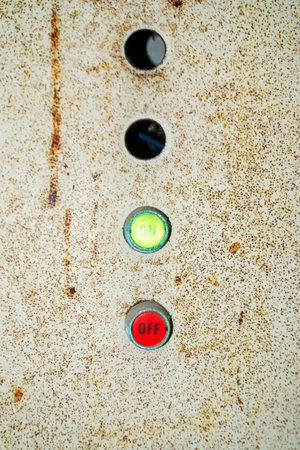 Close-up view of an industrial control panel showcasing an on button in green and an off button in...