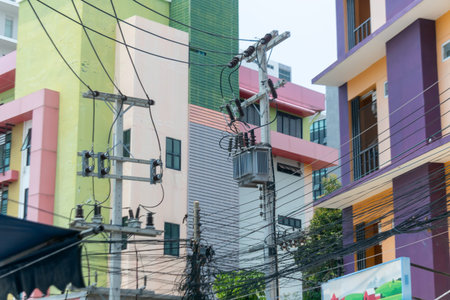This urban scene features power lines and a transformer against a backdrop of vibrant buildings,...