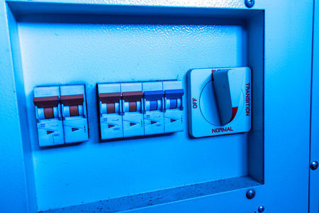 A close-up view of an electrical control panel featuring circuit breakers and a power switch. The...